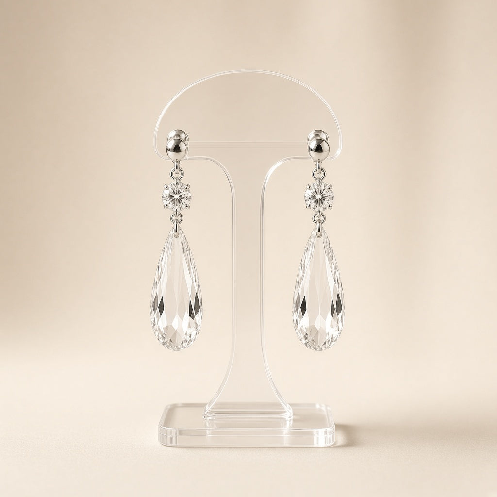 Silver crystal teardrop dangle earrings on a display stand