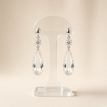 Silver crystal teardrop dangle earrings on a display stand