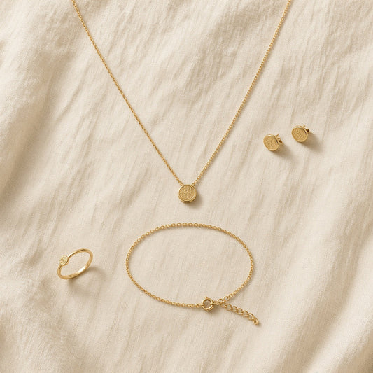 Gold coin necklace, bracelet, studs and ring flat lay