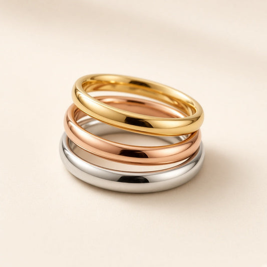 Three stacked stainless steel rings in gold, rose gold and silver