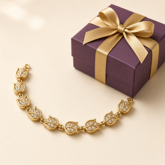 Gold plated tulip charm bracelet with crystals beside a plum gift box